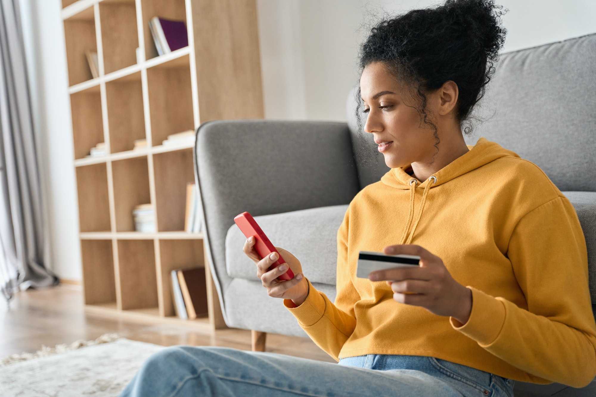 young adult african american girl sitting indoors doing mobile payment online